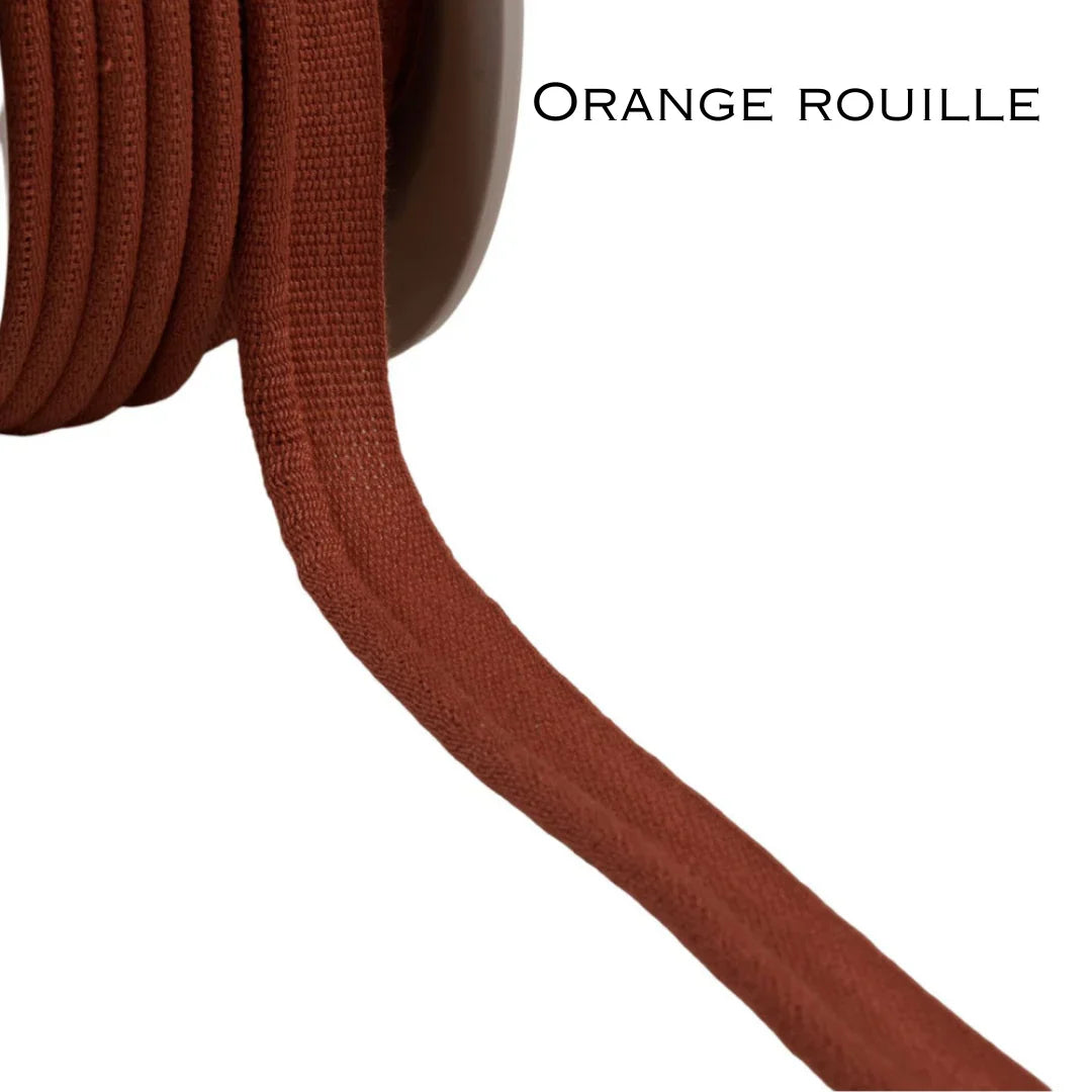 Spool of rust orange obi-kimono fabric trim on white background