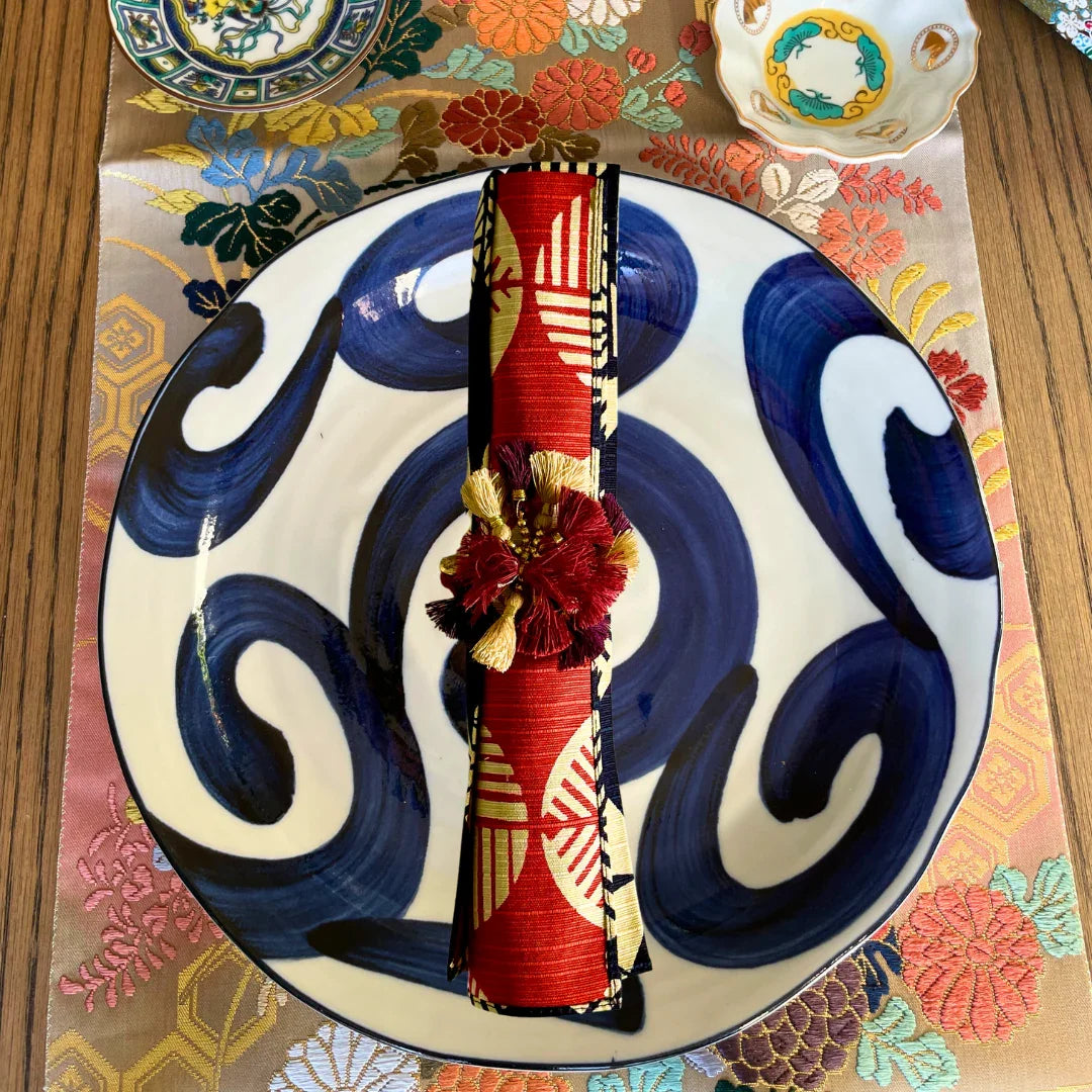 Elegant Japanese table setting with blue wave plate, obi-style napkin, and floral mat