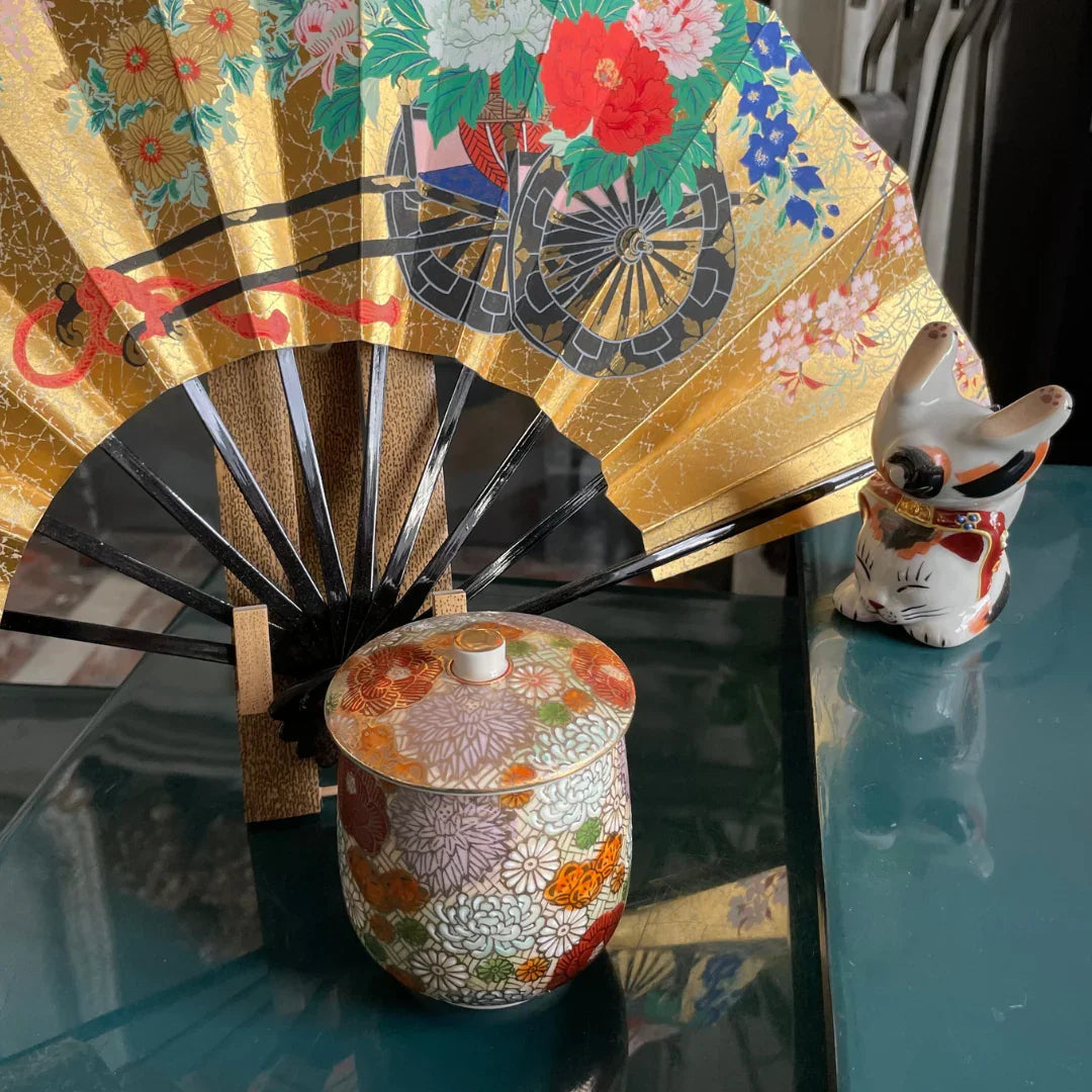 Japanese Kutani porcelain jar with floral design, gold decorative fan, and ceramic lucky cat figurine