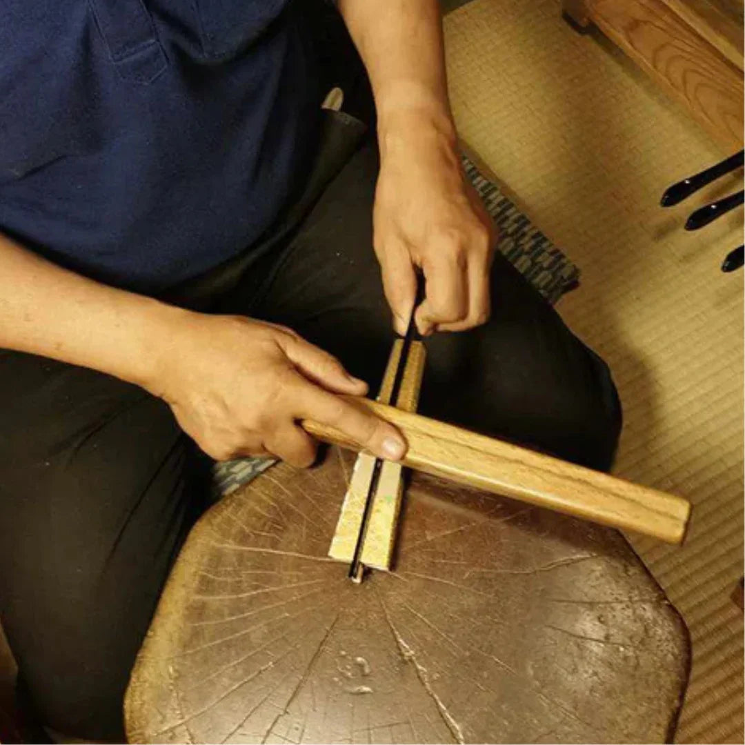 Artisan crafting kimono obi fabric with traditional Japanese woodworking tools