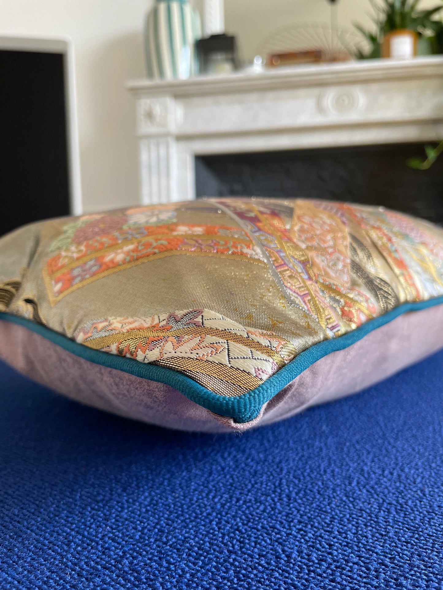 Vintage Japanese Obi-Kimono cushion with patterned silk fabric and teal trim on blue surface