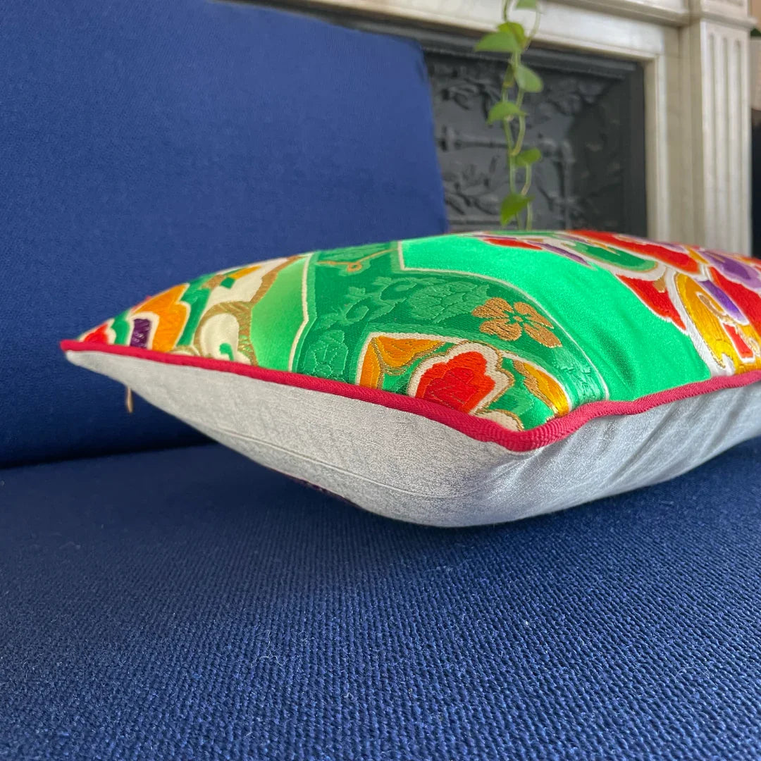 Vintage Obi Kimono cushion with vibrant green, red, and gold patterns on a blue sofa.