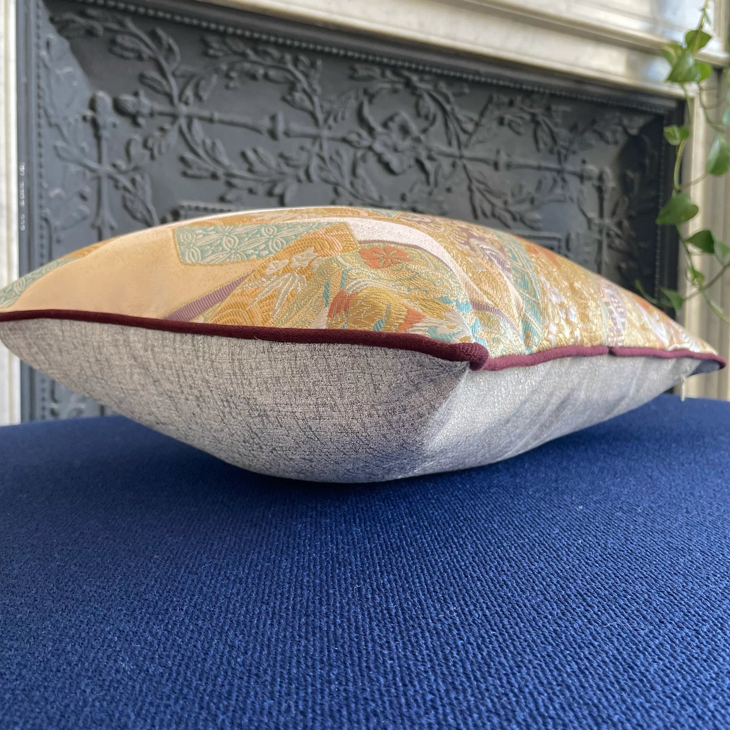 Vintage Obi-Kimono decorative cushion with intricate gold and floral patterns on a blue surface