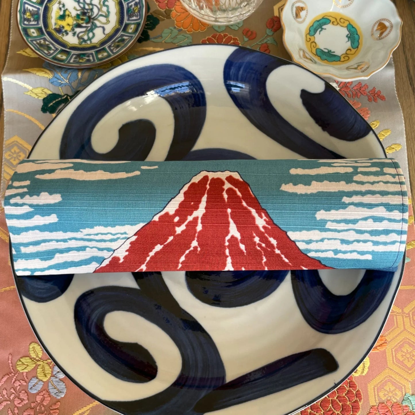Japanese table setting with vintage Mt. Fuji obi napkin, porcelain plates, and Kutani dishes