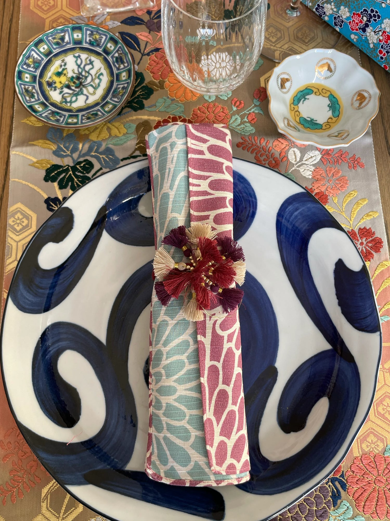 Elegant Japanese table setting with porcelain plates, kimono napkin wrap, and floral decor
